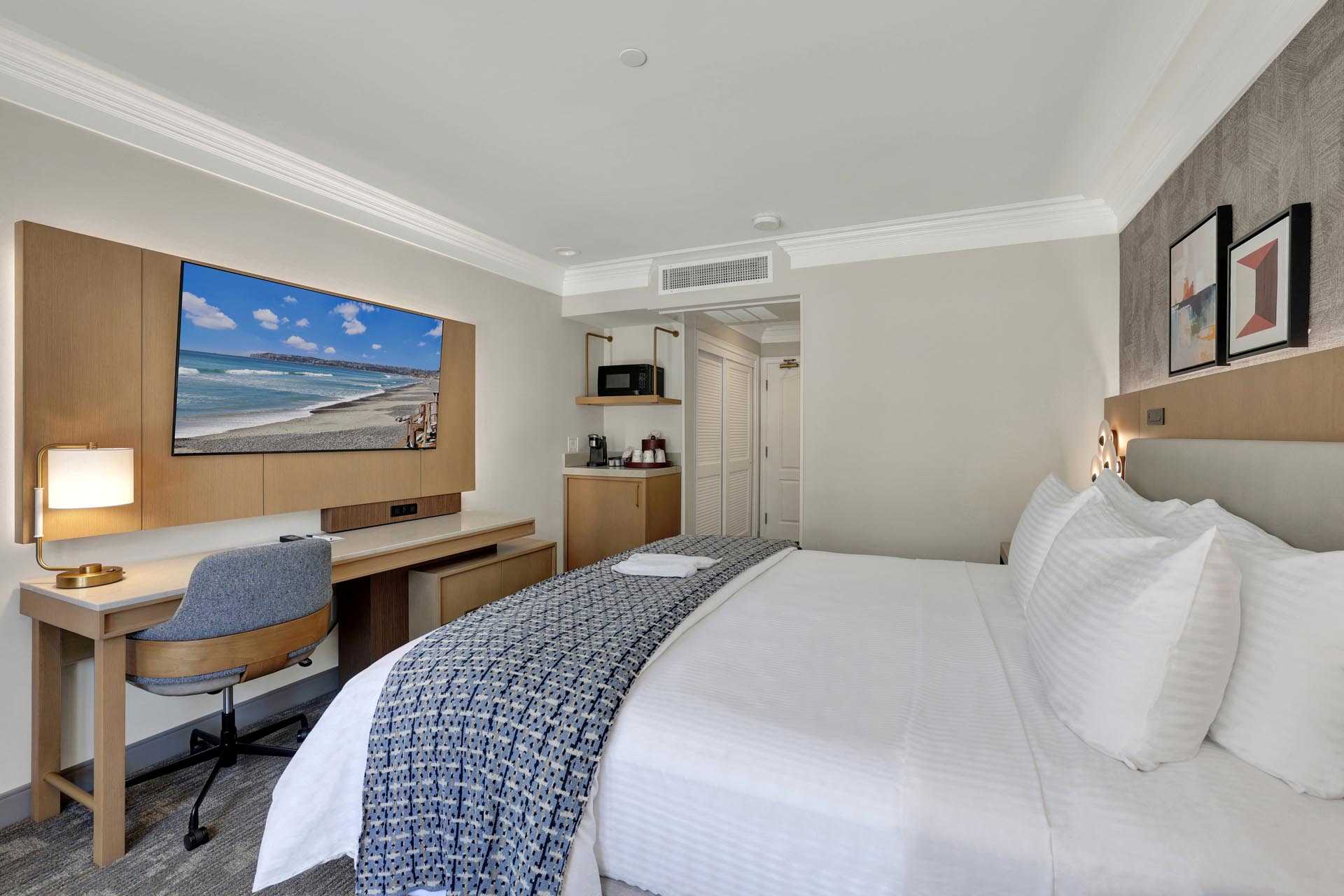 A king bed in front of a desk in a guest room